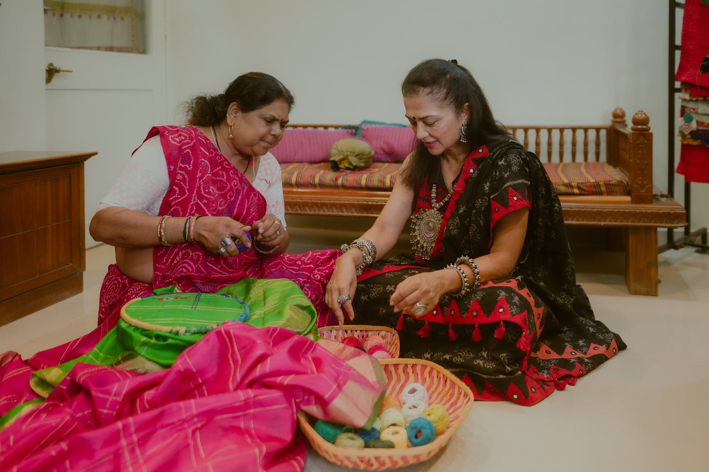 Aparna Patel seated with an Arishi Studio artisan among textiles and threads